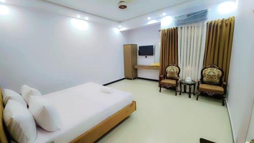 Comfort Lodge في كراتشي: غرفة فندق مع سرير وكرسيين