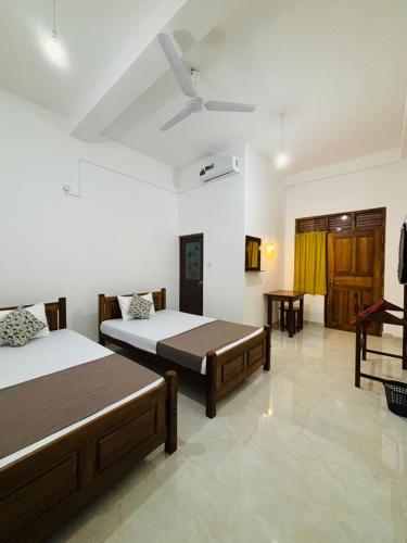 a bedroom with two beds and a ceiling fan at Brampy Guest in Polonnaruwa
