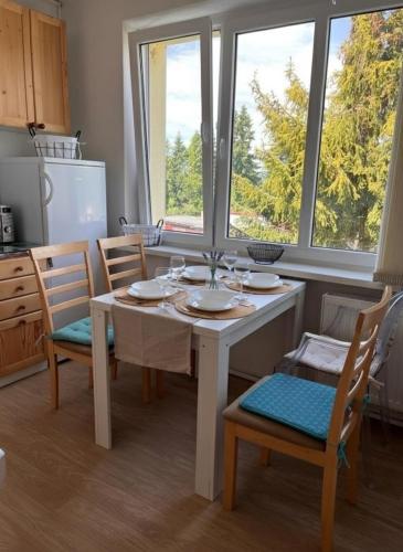 a kitchen with a white table and chairs and windows at Cozy Apartment by the Forest in Tatranska Strba