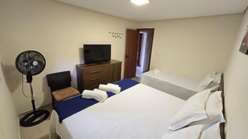 ブルマジーニョにあるCasa de Nair Pousadaのベッドとファン付きの客室です。