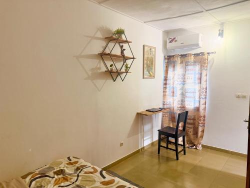a room with a bed and a chair and a desk at Résidence comme à la maison in Lomé