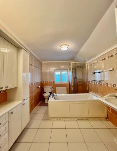 a large bathroom with a tub and a toilet at Three Bees in Hythe