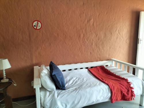 a bedroom with a white bed with a red blanket at Cango's Rest in Oudtshoorn
