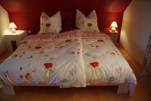 a bed with a white comforter with flowers on it at Panoramablick Höllbachtal in Rettenbach