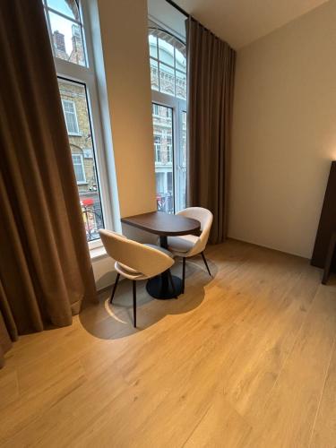 una stanza con un tavolo e due sedie e due finestre di Manteka Logies a Ypres