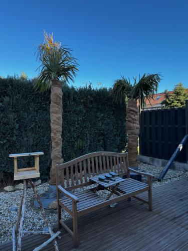 Un banco de madera en una terraza de madera con dos palmeras. en Zum Herold, en Thale