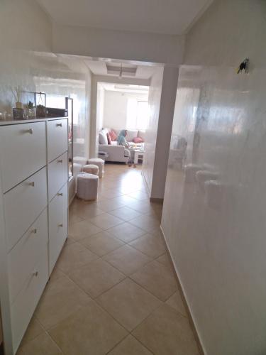 apartement avec piscine résidence sécurisée meublé confort jnan dalia Boznika في بن سليمان: مطبخ بدولاب بيضاء وأرضية بلاط