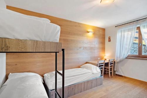 a bedroom with two bunk beds and a desk at Sunny Arabba Apartment in Arabba