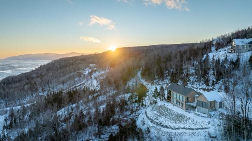 a house on the side of a snow covered hill with the sunset at La Bergerie in Saint-Joseph-de-la-Rive