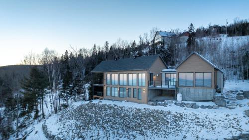 a house in the woods with snow on the ground at La Bergerie in Saint-Joseph-de-la-Rive