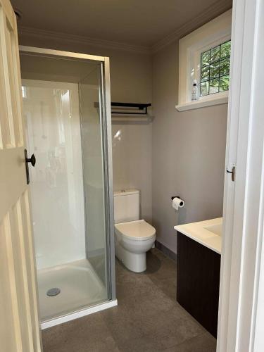 a bathroom with a toilet and a glass shower at Kina Beach Cottages in Tasman