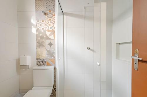 a white bathroom with a toilet and a shower at Casinhas Terõ - in Boracéia