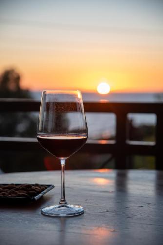 un bicchiere di vino seduto su un tavolo con il tramonto di Mounda Beach Retreat a Skala di Cefalonia