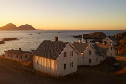 een groep huizen voor de oceaan bij zonsondergang bij Arctic Nest in Nyksund