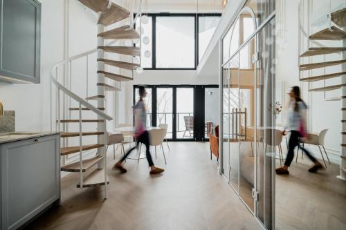 two women walking through a room with a spiral staircase at Zegrze Lake Apartament przy Narwi LEKKO z sauną in Zegrze