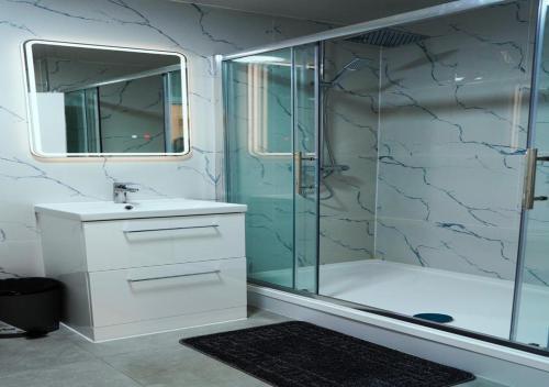 a bathroom with a glass shower and a sink at SS Sunrise & Silk in Bersted