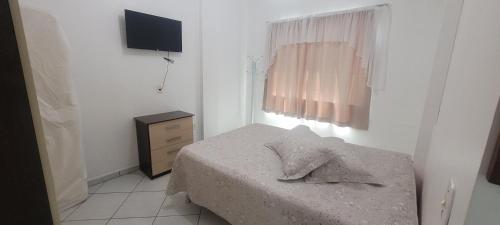 a bedroom with a bed and a dresser and a television at Edifício Vitória 1 Apt 203 in Marcelino Ramos