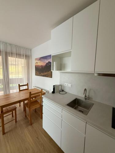 a kitchen with white cabinets and a table and a sink at Penzion Biely Potok in Terchová