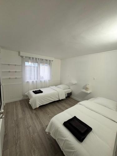 two beds in a room with white walls and wooden floors at Charmant Rez de Jardin 6 p 2 chambres et Parking in Savigny-sur-Orge
