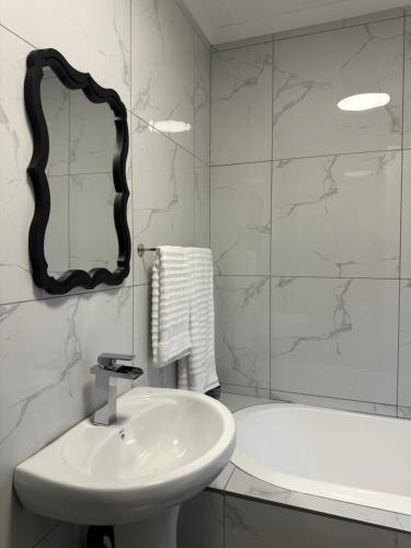 een badkamer met een wastafel, een spiegel en een bad bij Pendleberry Grove 33 in Bela-Bela