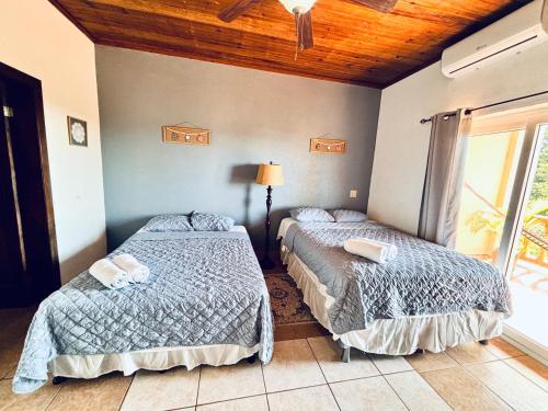 two beds in a room with a window at Sunset Views Apartment, West End in West End