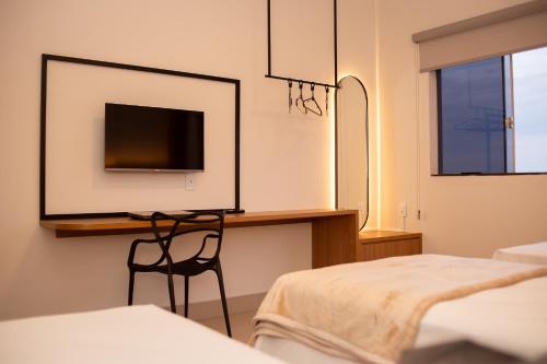 een slaapkamer met een bureau, een tv en een stoel bij Apart Hotel Roda Viva in Abaeté