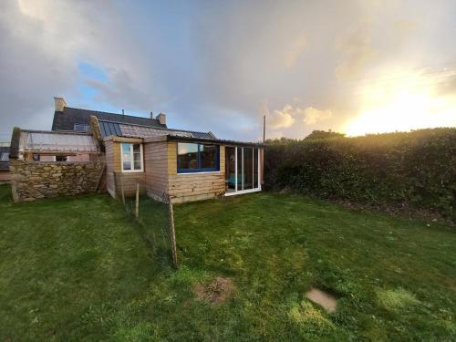 una piccola casa in un campo con il sole sullo sfondo di Gîte & studio de l'Holothurie a Plouguerneau