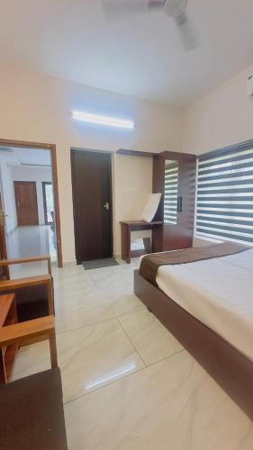 a bedroom with a bed and a desk and a table at TAMARA VISTA Executive Homestay in Varkala