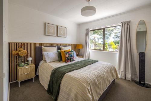 Blissful on Bay by Waiheke Pure في Waiheke Island: غرفة نوم بها سرير ونافذة