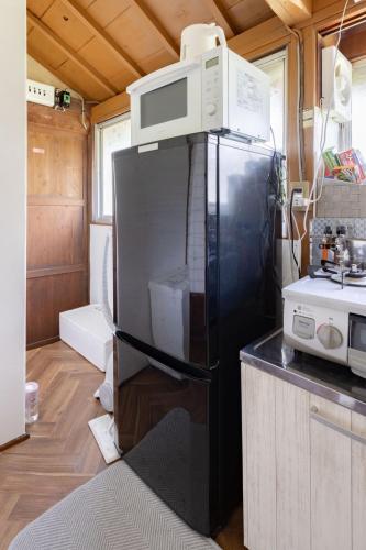 a refrigerator with a microwave on top of it in a kitchen at 温故知新 in Minamiboso