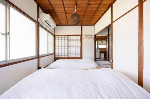 two beds in a room with windows at 温故知新 in Minamiboso