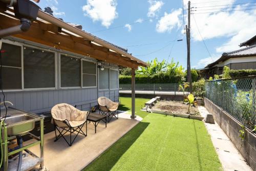 a patio with grass and chairs on a house at 温故知新 in Minamiboso