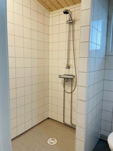 a shower in a bathroom with white tiled walls at Brusta Stugor in Ödkarby