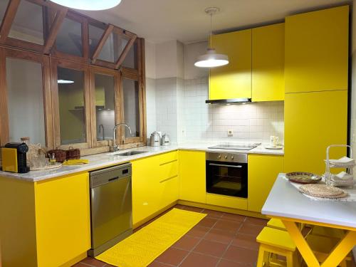 a yellow kitchen with yellow cabinets and a table at A Avozinha - Arouca in Arouca