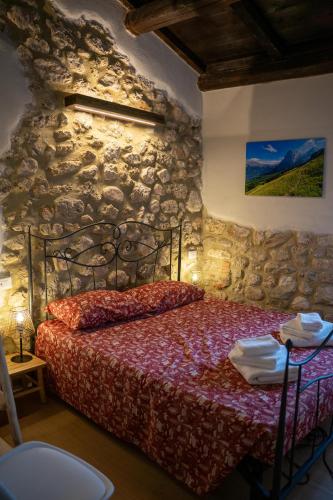 a bedroom with a bed in a stone wall at B & B Il bivacco in Assergi