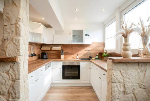 a kitchen with white cabinets and a stone wall at MILPAU Bottrop1 - Zentrales, modernes Design-Apartment - Smart TV, Nespresso, für 4 Personen in Bottrop
