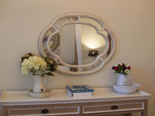 a mirror on top of a dresser with flowers on it at Melograno Apartments and Studios in Kala Nera