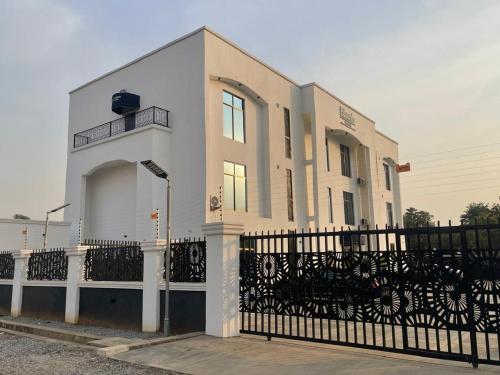 a white building with a black fence in front of it at Eduardo Hotel in Dushekoro