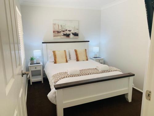 a bedroom with a white bed with two night stands at Bronte Lodge, Wine Country Farm Stay Hunter Valley with Games Room, Close to Town in Greta Main