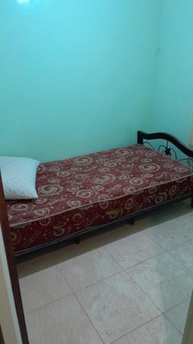 ein Bett in einem Zimmer mit einer rot-weißen Decke in der Unterkunft Nasmita's in Aourir