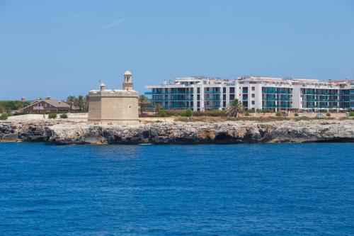 a view of a resort from the water at Aparthotel Caprice Skyline in Ciutadella