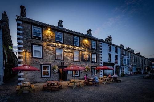 The Kings Arms Hotel في ريث: حانة بها طاولات ومظلات أمام المبنى