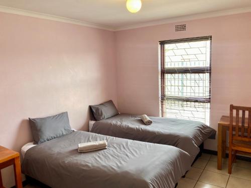 BelharUnit 1 GatherPoint Sleeps 6 Self-Catering Group in Belhar, Cape Town的房间里有两张床，还有一张桌子和一扇窗户