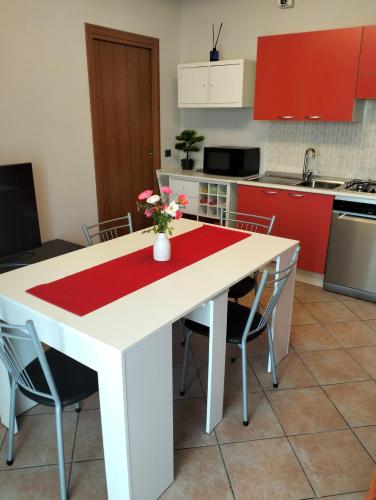 Roero House في Canove: مطبخ مع طاولة بيضاء ودواليب حمراء