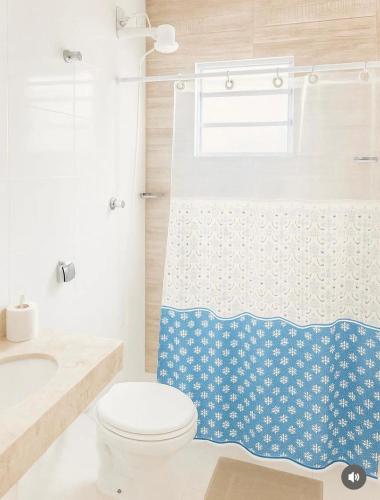 a bathroom with a toilet and a shower curtain at Palace Massaguaçu in Caraguatatuba
