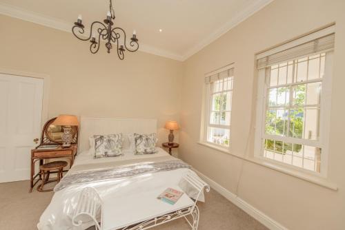 una camera da letto bianca con un letto e due finestre di Charming Historic Home in Central Stellenbosch a Stellenbosch