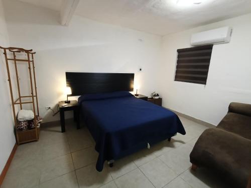 Un dormitorio con una cama azul y un sofá. en Departamento cerca del aeropuerto, en Chihuahua