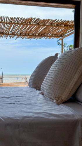 a bed with pillows and a view of the beach at Kiterise Tatajuba in Tatajuba