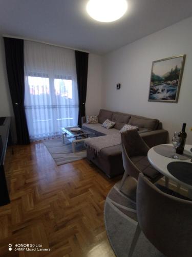 een woonkamer met een bank en een tafel bij Splendid J&R apartman in Bijeljina