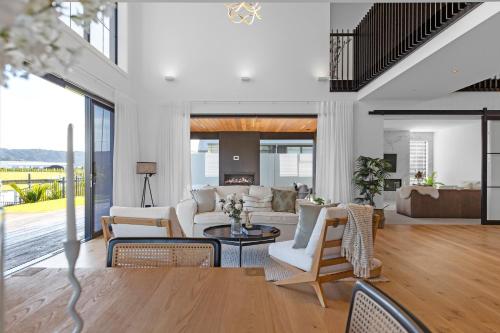 a living room with white furniture and large windows at Luxury Beach Retreat - Mountain Views & Boat Jetty in Whitianga